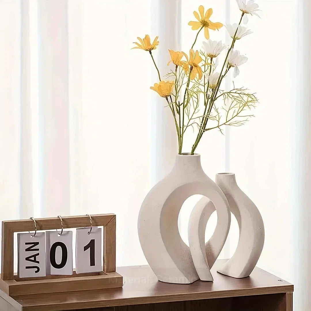 Two white vases with yellow and white flowers on a wooden surface with a calendar displaying January 1st.
